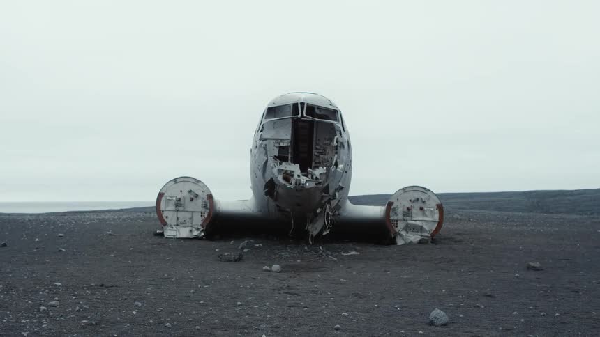 A crashed aircraft is sitting on open land under a milky white sky