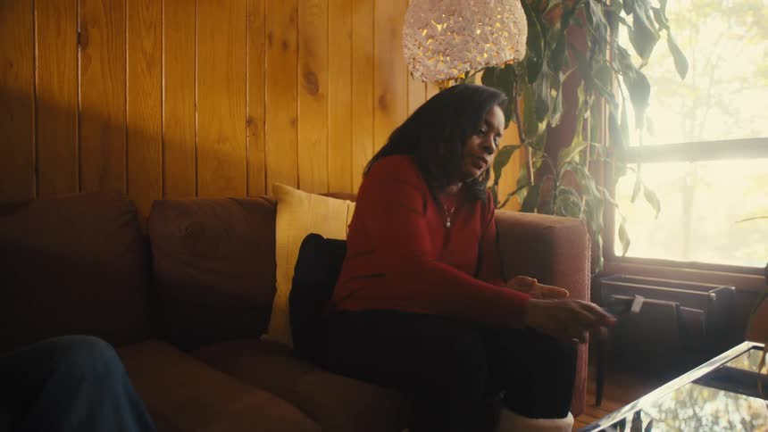 People are using devices in the living room and a woman puts down her phone