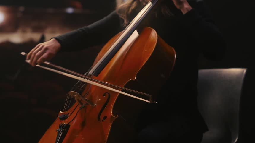 A woman is in a theater playing the cello