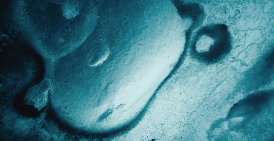 Light shines on droplets on a blue surface with textured areas and shadows