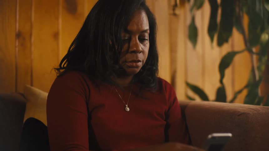 A woman is sitting on a couch and texting on her phone