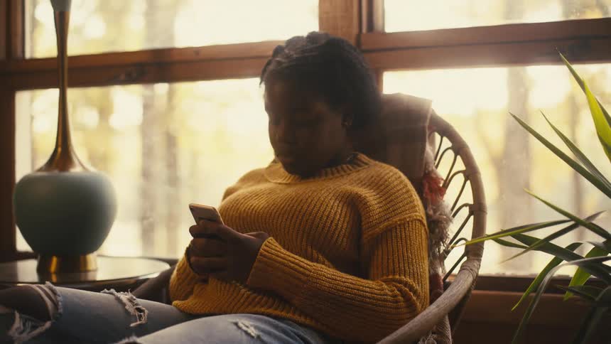 A woman using a smartphone talking to another woman