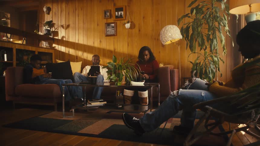 A family with teenagers using phones and tablets while sitting in a living room