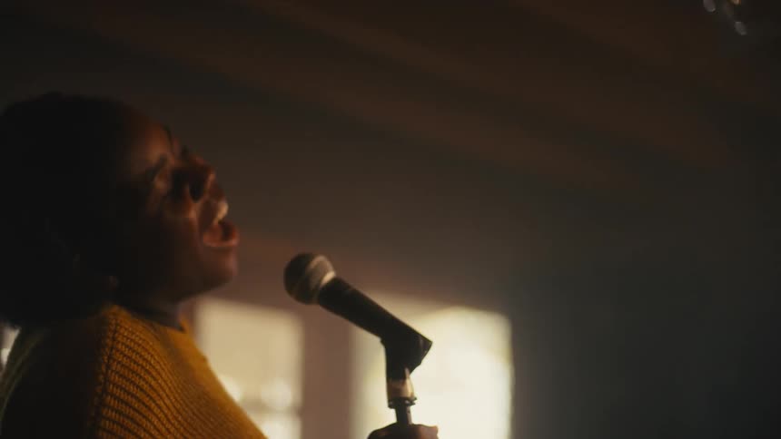 A woman is singing with a microphone indoors