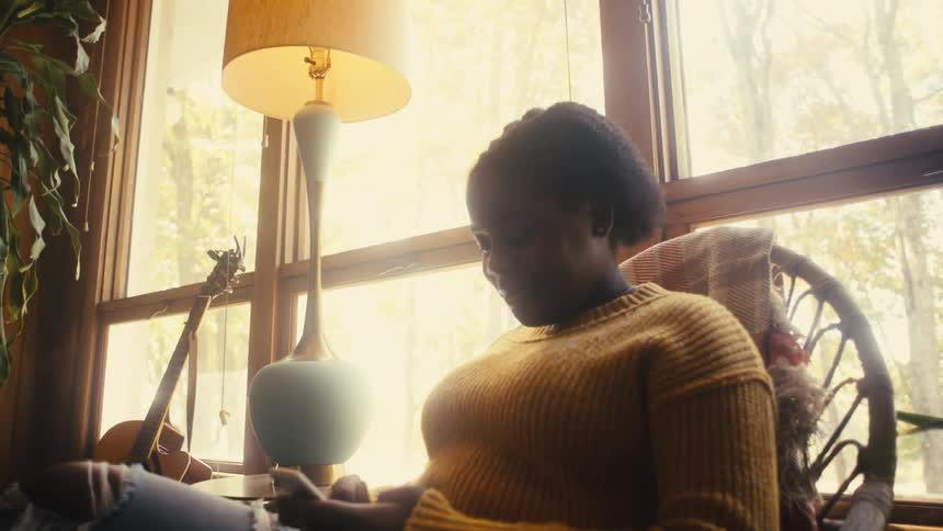 A young woman uses smartphone while sitting in a chair indoors during the day