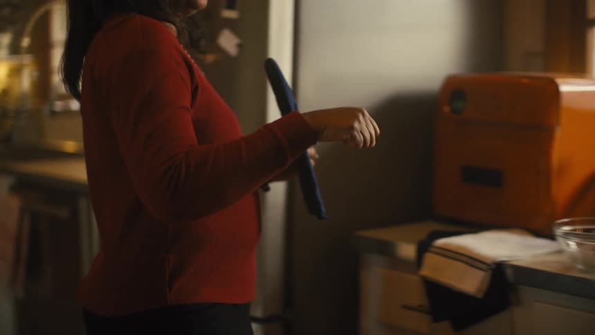 Mother walks into kitchen picking up oven mitt and fist bumping her son