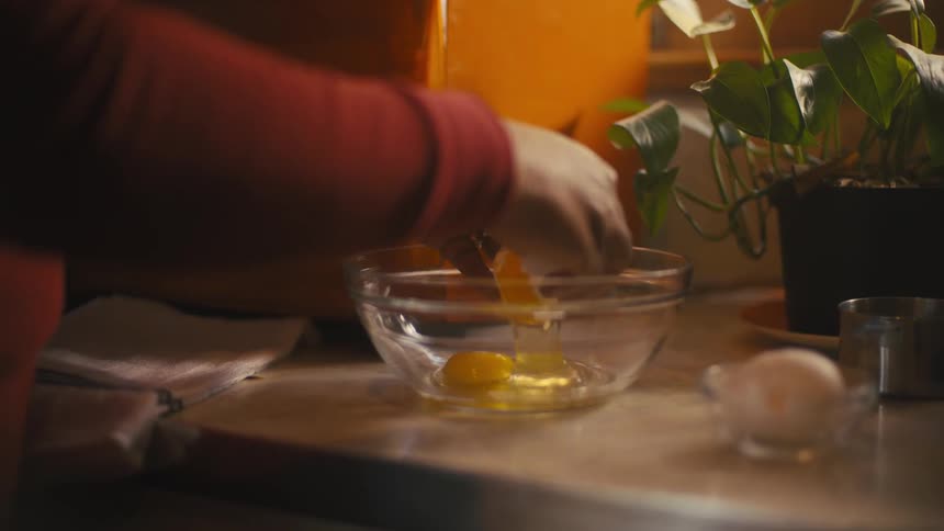 A woman is cracking eggs into a bowl