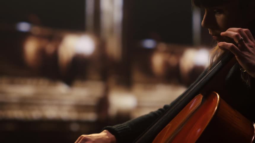 A female musician playing a cello indoors