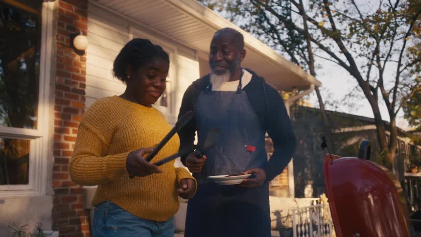 Older man smells food served from grill by woman and smiles before putting on table