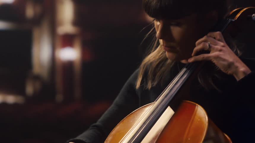 A woman is in a theater playing the cello