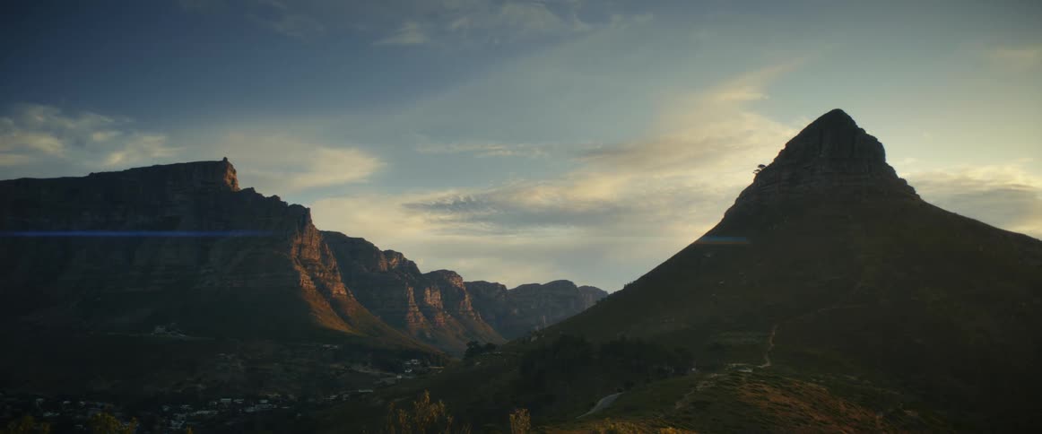 Clouds move over a mountain range and a mountain valley community