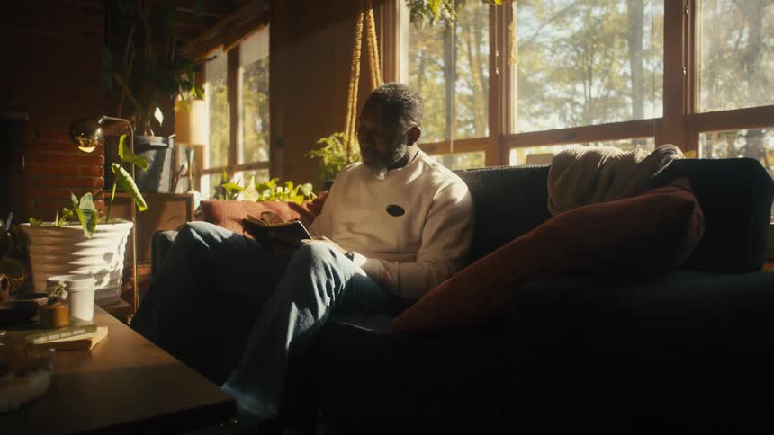 A man is sitting on a couch and writing in a journal