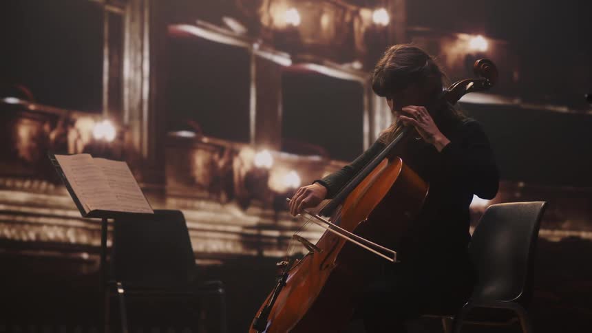 A female musician playing a cello on a stage