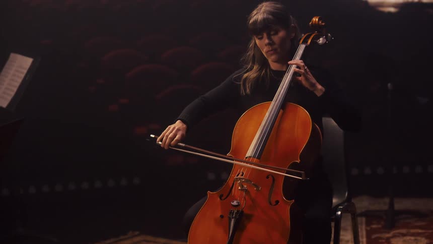 A woman is sitting down and playing an instrument