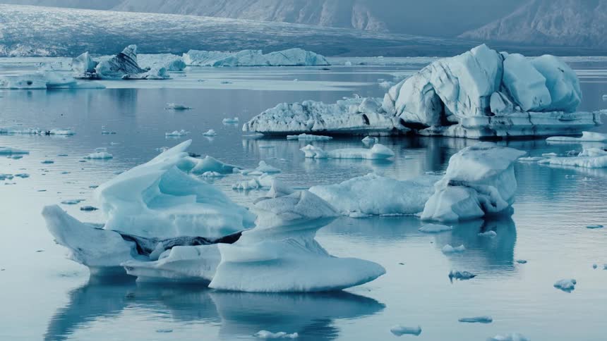 Water reflects floating sea ice near icy beach