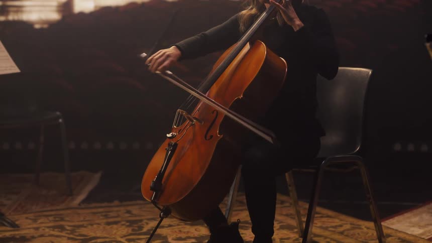 A female musician playing a cello on a stage