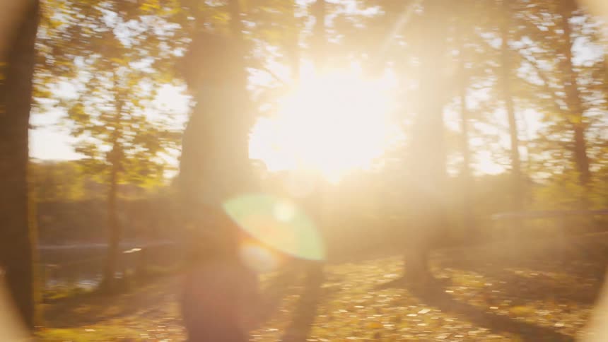 A mother and father play football with their son and daughter by a lake