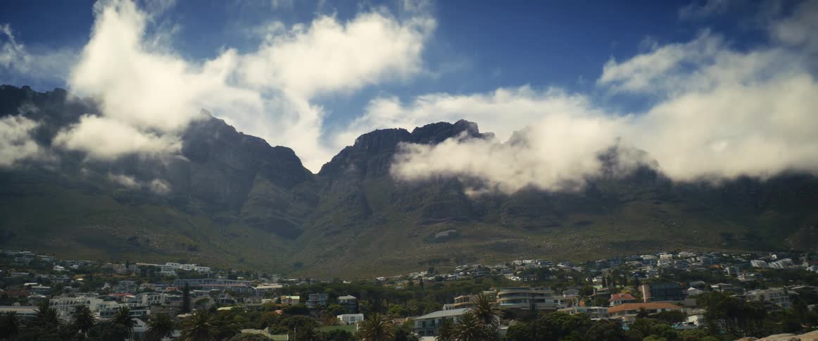 Clouds covering mountain near town disperse