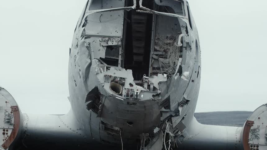 Wires hang from abandoned plane wreck sitting on bare ground