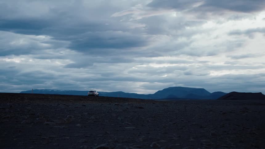 An suv traveling on a remote road on a cloudy day
