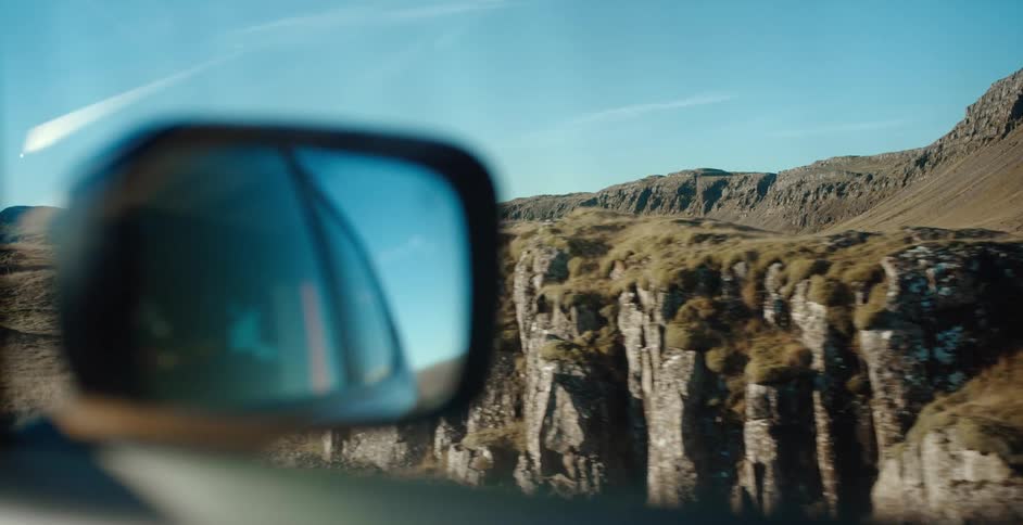 Rocks in the foreground and hills in the background as seen from a car window