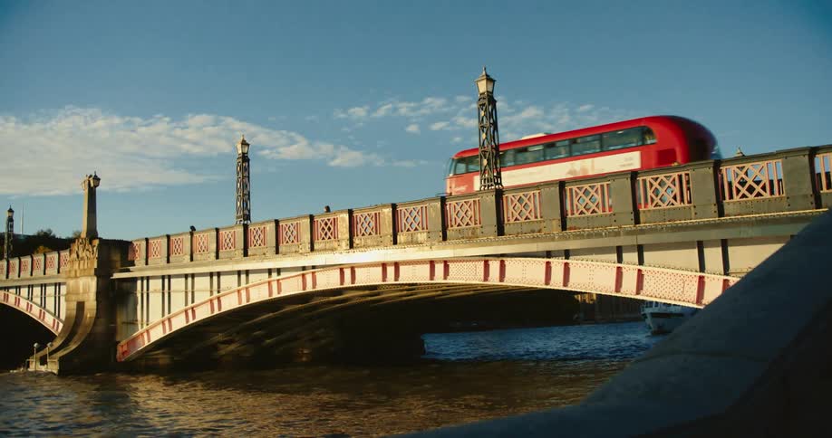 London double decker bus crosses bridge over river thames passing pedestrians