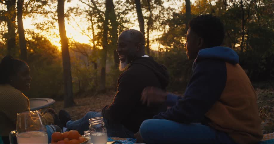 Family is outdoors eating and drinking around the nature area
