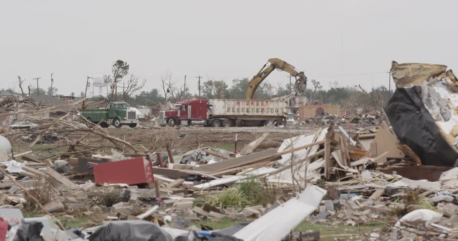 Trucks and construction equipment working to clear a neighborhood that has been destroyed