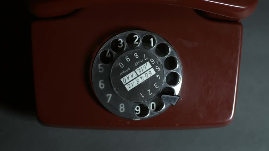 A man dials an old rotary phone