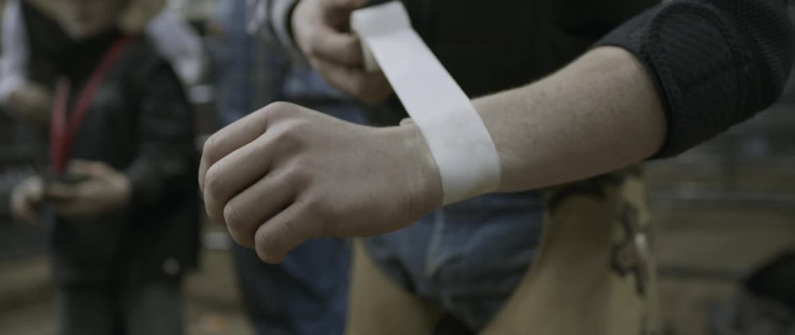 A cowboy wrapping athletic tape around his wrist at a rodeo