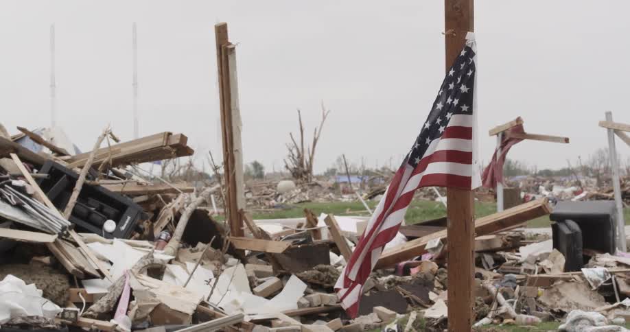 A flag hangs in front of destroyed homes