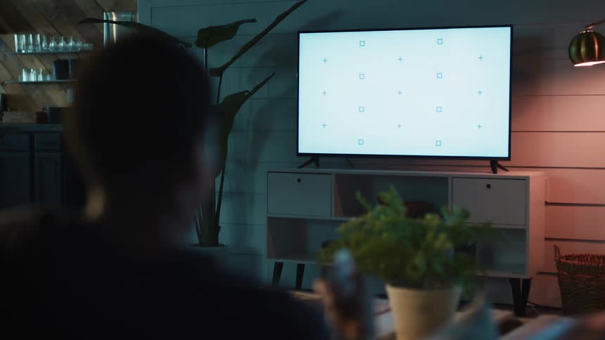 A person is holding their cell while watching television