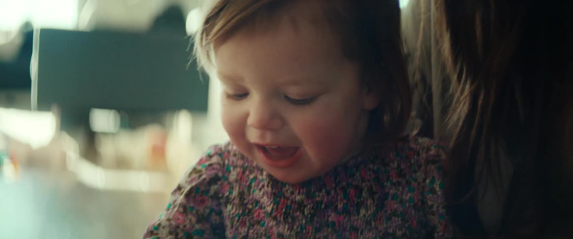 A smiling toddler girl sitting with her mother