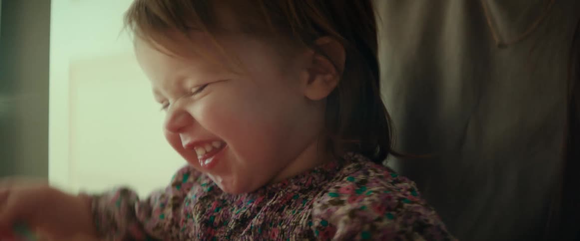 A toddler smiling while holding and shaking a book