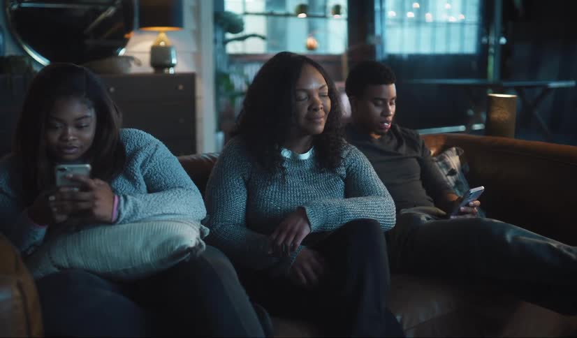 A family sit on the couch using their cell phones
