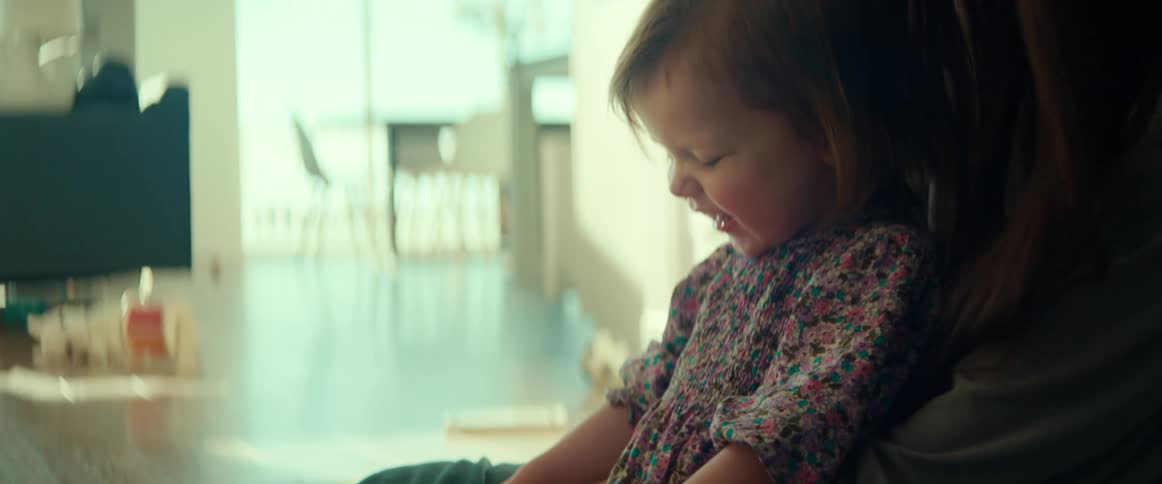 A mother sitting on the floor and playing with her baby