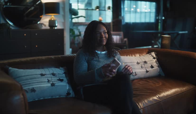 A woman is using her phone and watching tv
