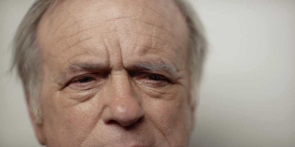 An elderly man looks worried as he shifts his head from one side to the other