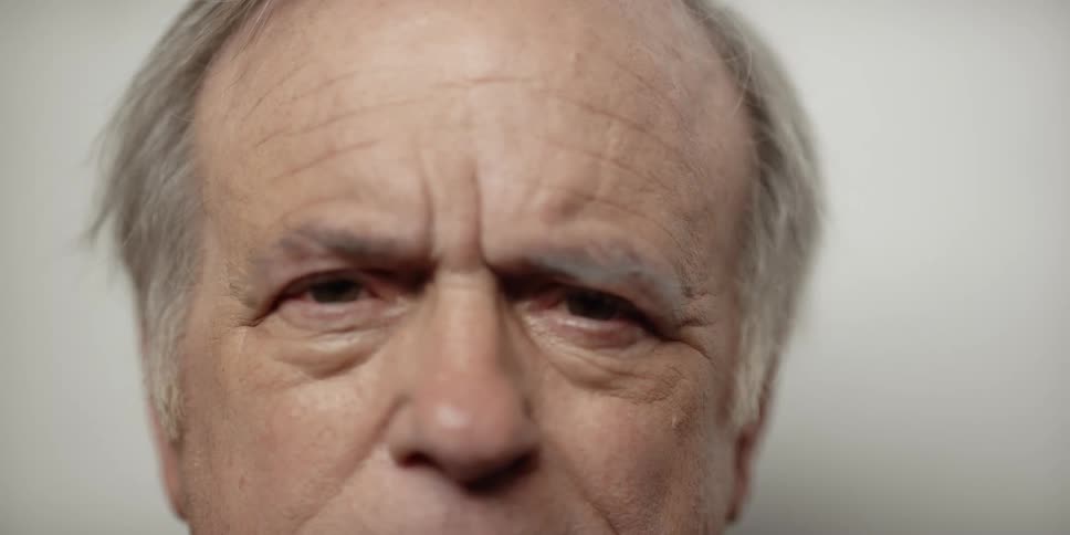Elderly balding man lifts his head to stare