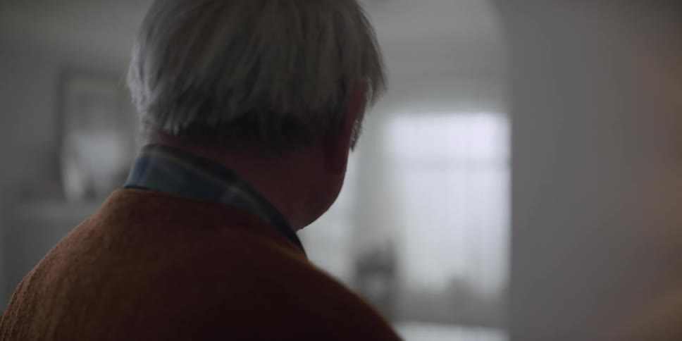 An elderly man is walking in his living room