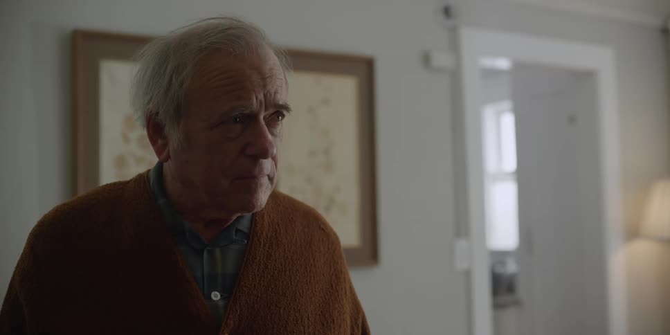 A man closes his eyes tightly while standing in his living room