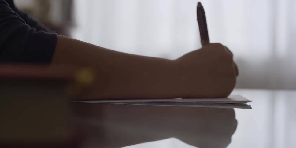 Person sitting at desk writes down in a sheet of paper