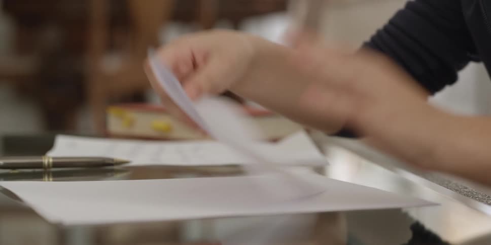 A child is holding a pen and writes a note on paper and then folds it and takes it