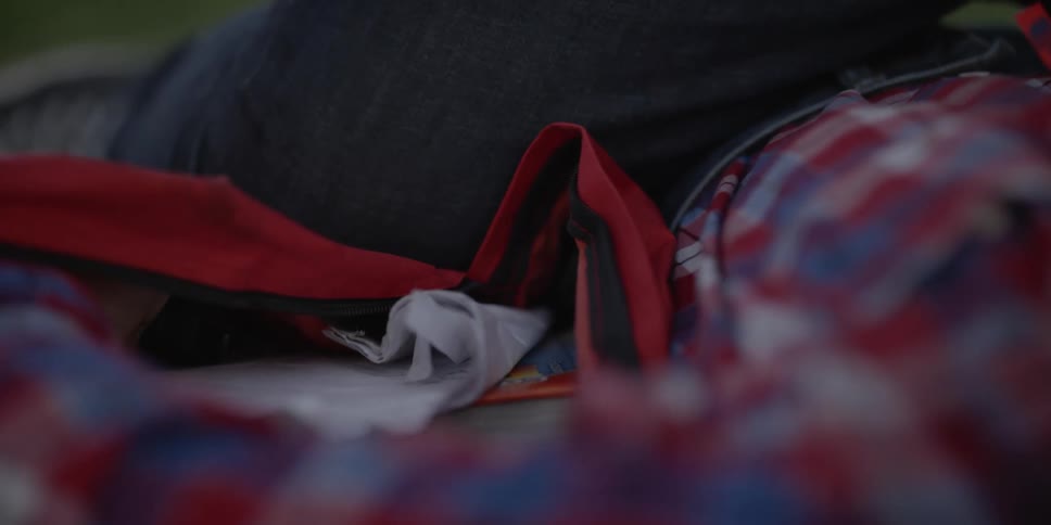 A person rummages through their tote bag while sitting outside