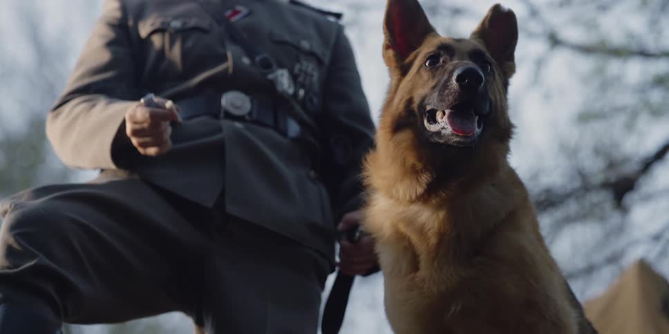 A soldier standing next to a dog and smoking a cigarette