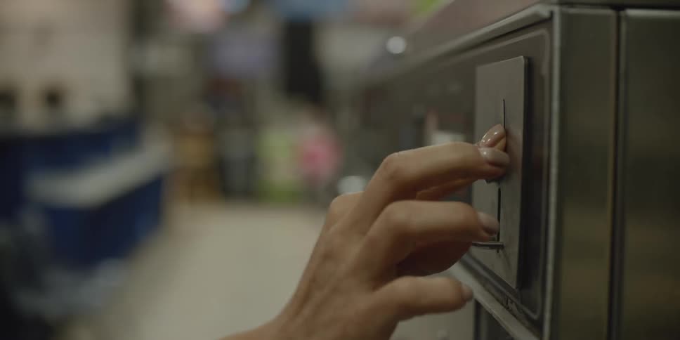 A woman puts a coin in to a machine