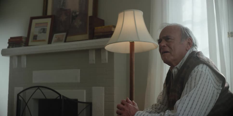 An elderly man looking sad while a man gets up abruptly and leaves