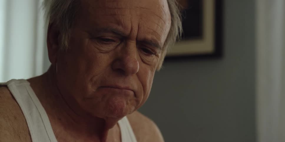 An elderly man is sitting in his house