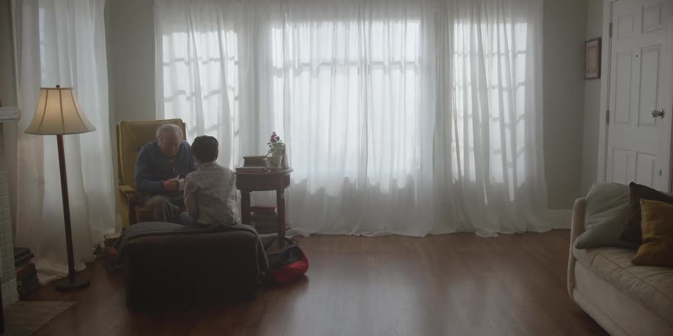 Boy sits with grandfather and watches as elderly man reads letter he gave him