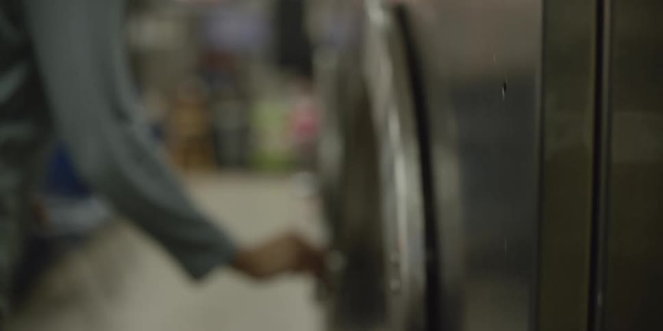 A man opens the door to a washer at a laundromat
